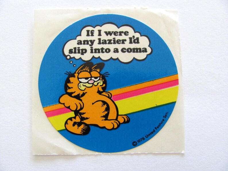 May include: A round sticker featuring Garfield the cat with a thought bubble that says "If I were any lazier I'd slip into a coma". The sticker has a blue background with a rainbow stripe and the copyright information "&copy; 1978 United Feature Syn."