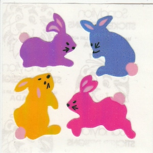 May include: Four colorful bunny stickers with a glossy finish. The bunnies are purple, blue, yellow, and pink.