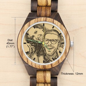 May include: A wooden wristwatch featuring a light-colored dial with a custom engraved portrait of a smiling couple. The watch has a dark and light wood grain band, a 45mm (1.77 inch) diameter dial, and a case thickness of 12mm as indicated by text.