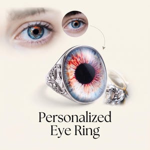Pode incluir: Um anel de prata com um grande cabochão oval apresentando uma impressão realista de um olho humano em tons de azul, laranja e preto. A banda de metal possui padrões intrincados de volutas em relevo. O texto Personalized Eye Ring está abaixo.