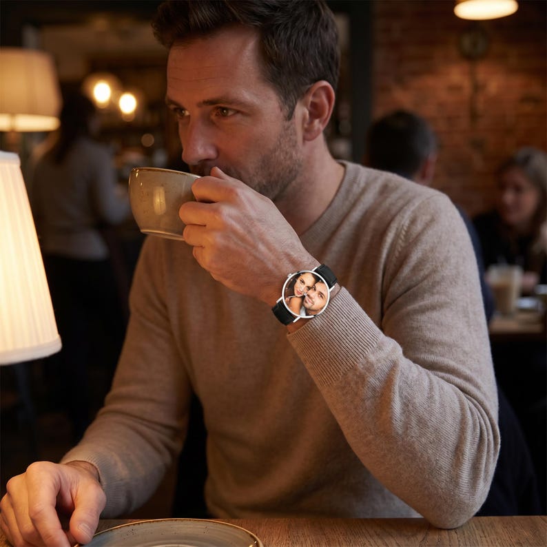 Peut inclure: Une montre-bracelet avec un cadran rond pr&eacute;sentant une photographie personnalis&eacute;e d'un couple. La montre poss&egrave;de une fine lunette en m&eacute;tal argent&eacute; et un bracelet en cuir noir. Le cadran affiche une image nette d'un homme et d'une femme souriants.
