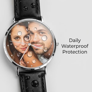 Peut inclure: Une montre-bracelet avec un bracelet en cuir noir et un bo&icirc;tier en m&eacute;tal argent&eacute;. Le cadran pr&eacute;sente une photographie personnalis&eacute;e d'un couple, recouverte de gouttelettes d'eau r&eacute;alistes. Le texte Daily Waterproof Protection est inscrit &agrave; droite.