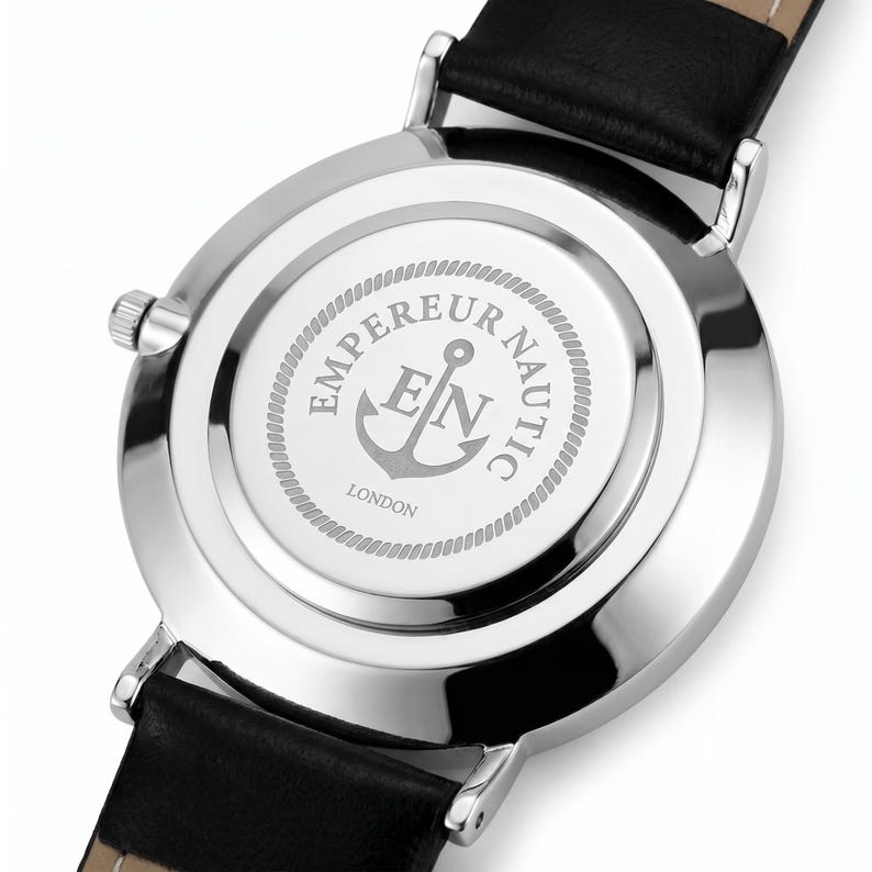Peut inclure: Un bo&icirc;tier de montre argent&eacute; avec un bracelet en cuir noir. Le dos m&eacute;tallique circulaire pr&eacute;sente un logo d'ancre grav&eacute;, les lettres EN et le texte EMPEREUR NAUTIC LONDON entour&eacute;s d'un motif de bordure en forme de corde.