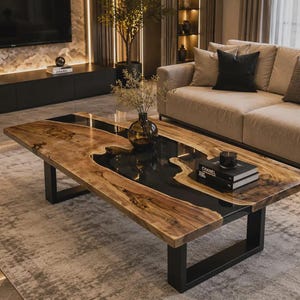 Pode incluir: Uma mesa de centro retangular com um tampo de madeira natural de borda viva e uma incrustação central de resina preta. A mesa é sustentada por duas pernas de metal preto em forma de U e exibe um vaso de vidro escuro e alguns livros.