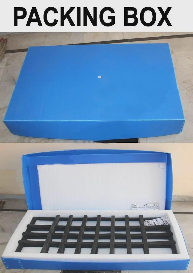 May include: Blue packing box with the text "PACKING BOX" in bold white letters. The box is open, revealing a white interior with a black grid-like structure. The box is designed for shipping and storage.