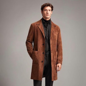 May include: A brown suede coat with a classic design. The coat features a notched lapel, two front pockets, and button closures. The model is wearing a black turtleneck and a patterned shirt underneath.