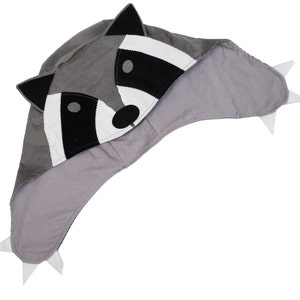 May include: Gray raccoon-shaped hooded hat with white and black details. The hood has a gray corduroy exterior and a soft gray lining.
