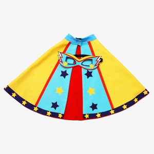 May include: A yellow, blue, and red superhero cape with a blue and yellow mask. The cape has stars and stripes and the mask has a lightning bolt design.