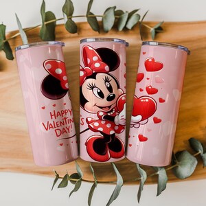 Op de afbeelding: Drie roze ge&iuml;soleerde bekers met Valentijnsdagontwerpen. E&eacute;n heeft Minnie Mouse in een rode polkadotjurk en strik, met een hart. Een andere heeft de tekst "Happy Valentine's Day!" en harten.