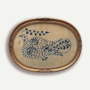 May include: Oval framed artwork featuring a blue and white folk art dove design. The bird is dotted and holds a sprig in its beak. The artwork is set in a gold-colored ornate frame, creating a vintage aesthetic.