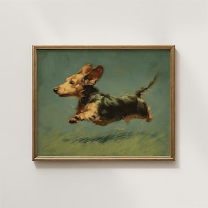 May include: A framed painting of a dachshund dog in mid-air, appearing to run or jump. The dog has brown and black fur, with its ears perked up. The background is a muted green with a hint of grass at the bottom. The frame is gold.