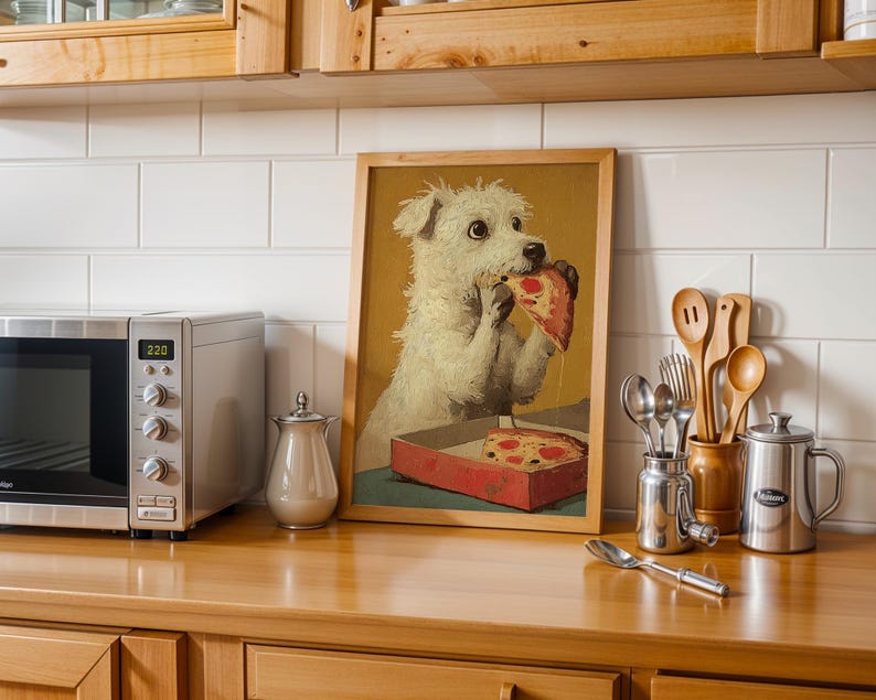 May include: A framed print of a white dog eating pizza, displayed on a wooden countertop. A stainless steel microwave, a small silver container, and kitchen utensils are also visible.