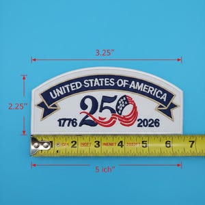 May include: A white embroidered patch with the text "UNITED STATES OF AMERICA 250 1776-2026". The patch is 5 inches long and 2.25 inches high. The text is in navy blue and red.