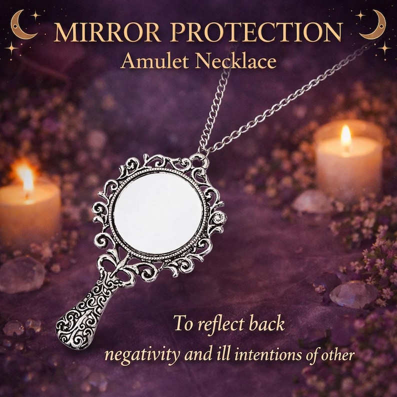 May include: A silver-toned metal pendant necklace featuring a small, round mirror set within an ornate, filigree-style frame with a handle. The text MIRROR PROTECTION Amulet Necklace and To reflect back negativity and ill intentions of other is visible.