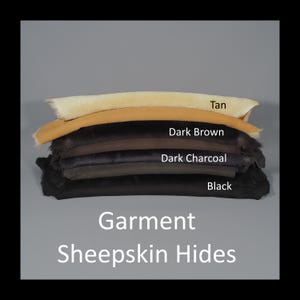 May include: A stack of garment sheepskin hides in various colors, including tan, dark brown, dark charcoal, and black. The hides are neatly arranged, with the color names labeled. The text "Garment Sheepskin Hides" is displayed at the bottom.