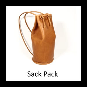 May include: A tan leather sack pack with drawstring closure and shoulder straps. The bag has a cylindrical shape with a rounded base. The text "Sack Pack" is displayed at the bottom of the image.