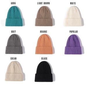 Könnte beinhalten: Eine Auswahl an gerippten Strickmützen in verschiedenen Farben, darunter Aqua, Hellbraun, Weiß, Grau, Orange, Lila, Creme und Schwarz. Die Wörter "AQUA", "LIGHT BROWN", "WHITE", "GREY", "ORANGE", "POPULAR", "CREAM" und "BLACK" sind über jeder Mütze zu sehen.