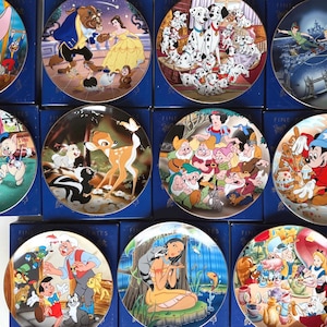 Può includere: Una collezione di piatti decorativi con vari personaggi e scene dei cartoni animati Disney. I piatti presentano personaggi come Dumbo, Belle e la Bestia, Bambi, Biancaneve, Topolino e altri. Ogni piatto è rotondo e presenta un'illustrazione colorata e dettagliata.