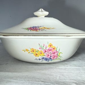 May include: A white ceramic mug with a black handle and the text "But First, Coffee" in a black, handwritten-style font. The mug is on a white surface.