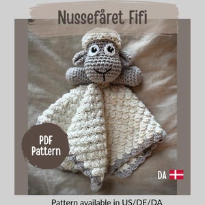 May include: A cream-coloured crocheted baby blanket in the shape of a sheep, with a grey border and a matching sheep head. The text "Nussefåret Fifi" and "PDF Pattern" are visible. The pattern is available in US/DE/DA.