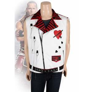 Puede incluir: Chaleco blanco sin mangas con cremallera negra, cinturón negro y cuello con estampado de cebra rojo y negro. Presenta un corazón rojo con una flecha, corazones negros y cadenas plateadas. El chaleco está en un maniquí.