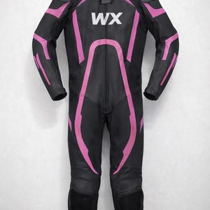 May include: Black and pink motorcycle racing suit with the letters "WX" on the chest. The suit has pink accents on the shoulders, arms, and legs. The suit is hanging on a black hanger.