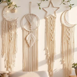 May include: Four cream-coloured macrame wall hangings in the shapes of a crescent moon, a circle, a star, and a second crescent moon. Each has intricate woven patterns and hanging fringe. The decor is bohemian and adds a natural, artistic touch.