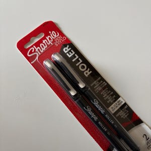 以下が含まれることがあります： 黒インクと0.5mmのニードルポイントを備えたSharpie Rollerペン2本セット。ペンは赤と黒のオリジナル小売パッケージに入っており、プラスチック製のブリスターカードの前面にはSharpie Pen StyloおよびRollerという文字がはっきりと印刷されています。