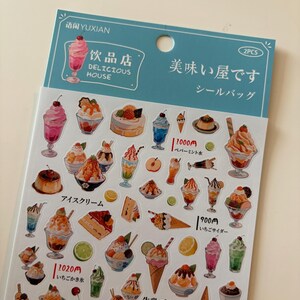 May include: A sheet of stickers with illustrations of Japanese desserts, such as parfaits, ice cream cones, and puddings. The stickers feature Japanese text and the words "Delicious House".