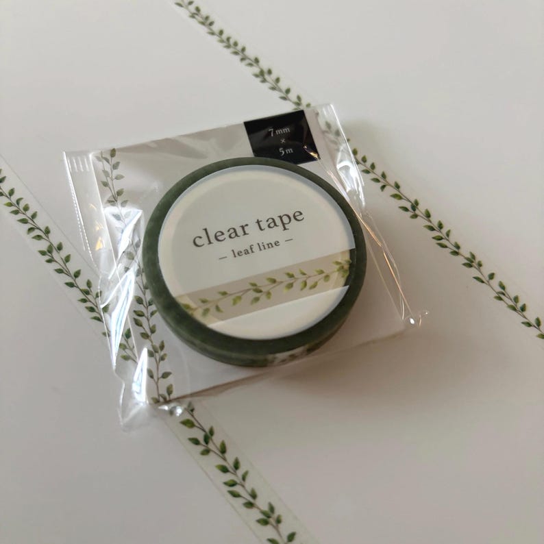 May include: A roll of clear tape with a leaf design, packaged in a clear plastic sleeve. The tape roll is labeled "clear tape - leaf line -" and measures 7mm x 5m.