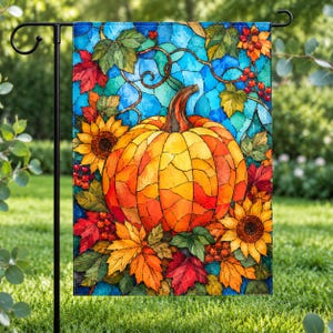 May include: A rectangular garden flag featuring a stained glass style illustration of a large orange pumpkin surrounded by yellow sunflowers, red and green autumn leaves, and small red berries against a vibrant blue geometric background.