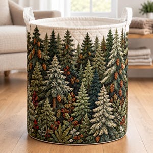 May include: A cylindrical fabric laundry basket featuring a detailed forest print with various evergreen trees, pinecones, and small red berries. The basket has a quilted cream-colored top border and two sturdy white fabric handles on the sides.