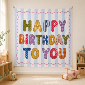 May include: A rectangular fabric wall hanging featuring a light blue and white vertical striped background with a pink wavy border. The text HAPPY BIRTHDAY TO YOU is displayed in large, multi-colored, patterned fabric letters.