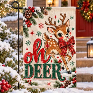 May include: A rectangular garden flag featuring a brown fawn with a red plaid bow around its neck. The text reads Oh DEER in red and green letters. The design includes pine branches, pinecones, red berries, and red and green snowflakes.