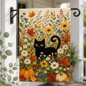 May include: A rectangular garden flag featuring a black cat standing in a field of autumn flowers, orange pumpkins, and colorful fall leaves. The design includes yellow sunflowers, white daisies, and blue wildflowers on a cream background.