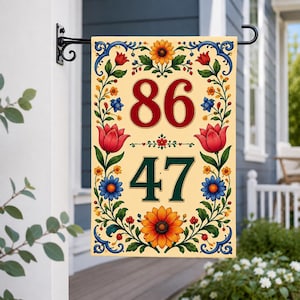 May include: A rectangular house flag featuring a cream background with the numbers 86 and 47 in red and dark green. The design is framed by a colorful floral border of sunflowers, red tulips, and blue flowers with green leaves and blue scrollwork.