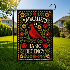 May include: A rectangular garden flag with a black background featuring a red cardinal bird perched on a branch. The text reads RADICALIZED BY BASIC DECENCY in cream lettering. The design includes yellow, red, and orange flowers with green leaves.