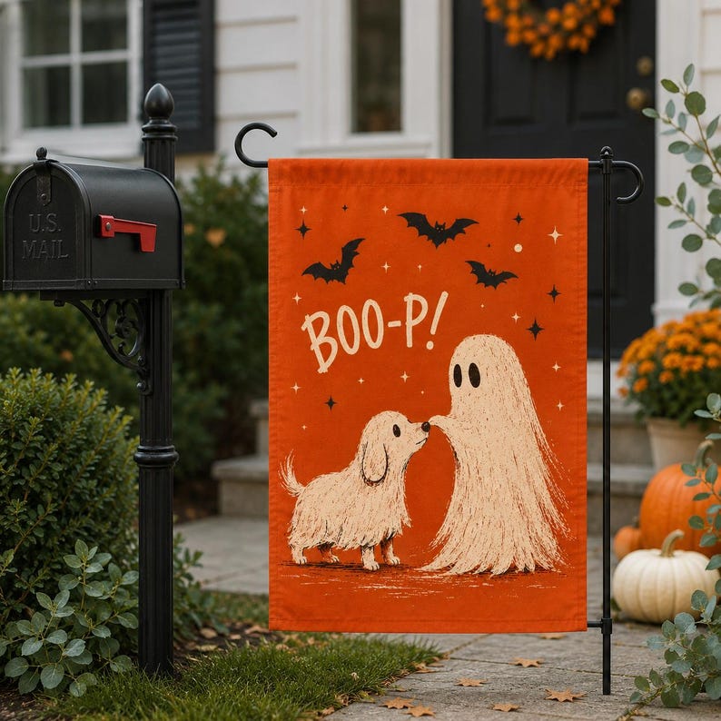 May include: A rectangular orange garden flag featuring a white illustration of a small dog and a ghost touching noses. The text BOO-P! is printed in white above the figures, surrounded by black bat silhouettes and small white star accents.