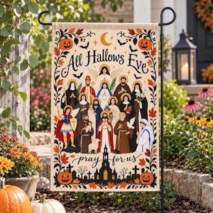 May include: A rectangular garden flag featuring a cream background with a border of autumn leaves and pumpkins. The text reads All Hallows Eve and pray for us. The center displays a group of religious figures, saints, and angels in robes.