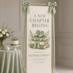 May include: A vertical banner featuring the text A NEW CHAPTER BEGINS, WELCOME TO OLIVIER JAMES'S BABY SHOWER 12.12.2026, with an illustration of baby shoes on stacked books, decorated with sage green ribbons on a gold metal frame stand.