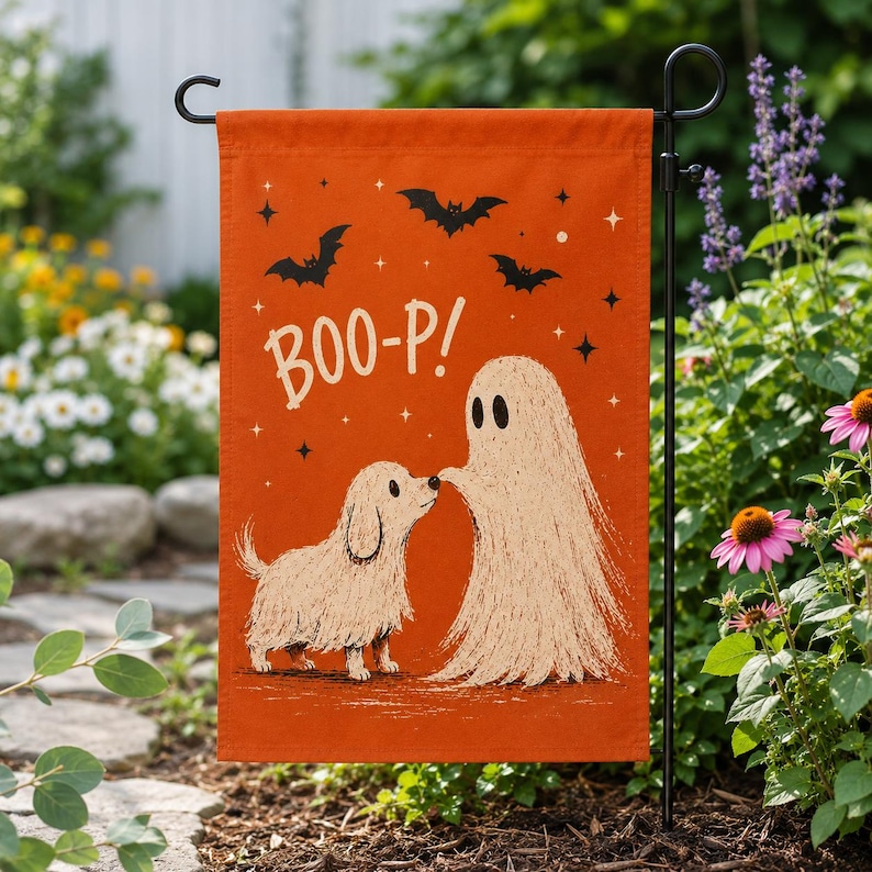 May include: A rectangular orange garden flag featuring a cream-colored illustration of a small shaggy dog and a ghost touching noses. The text BOO-P! is printed in white above the figures, surrounded by small black bats and star accents.