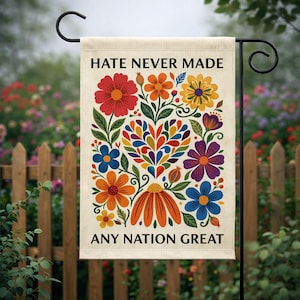 May include: A beige garden flag with the text "HATE NEVER MADE ANY NATION GREAT" above and below a colorful floral design. The flowers are red, orange, yellow, blue, and purple.