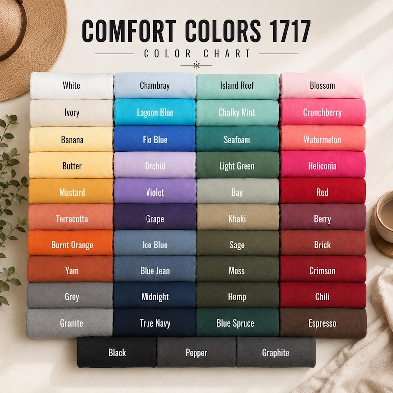 May include: A Comfort Colors 1717 color chart displaying a grid of folded fabric swatches in various shades. Each swatch is labeled with its specific color name, including White, Ivory, Banana, Butter, Mustard, Terracotta, Burnt Orange, Yam, Grey, Granite, Black, Pepper, Graphite, and many others.