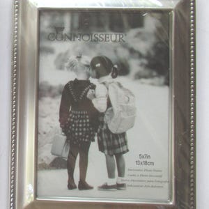May include: A silver-colored decorative photo frame with a beaded border. The frame holds a black and white image of two children. The frame is labeled "CONNOISSEUR" and is sized 5x7 inches (13x18cm).