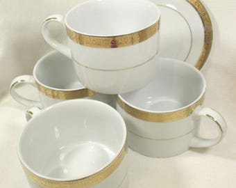 Cuatro tazas y dos platos de postre blancos con borde dorado de Studio Ten
