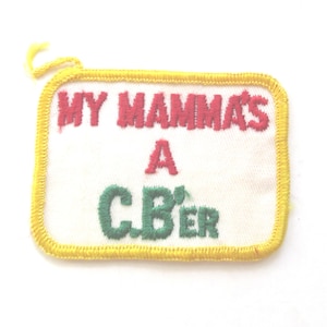 May include: Embroidered patch with the text "MY MAMMA'S A C.B'er" in red and green on a white background. The patch has a yellow border and a yellow loop at the top.