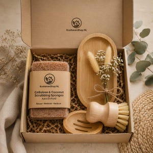 Op de afbeelding: Een geschenkdoos met cellulose- en kokos schuursponzen, een houten schaal, een houten borstel en een bamboe dienblad. De doos bevat gedroogde bloemen en is gevuld met bruin crêpepapier. De sponzen zijn 7 x 11 cm.
