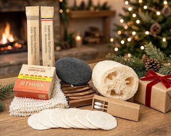 May include: A collection of personal care items including two bamboo toothbrushes in paper sleeves, a shampoo bar box labeled RTHINK, a dark gray pumice stone, a wooden soap dish, a loofah sponge, cotton rounds, and a gift box with a red ribbon.
