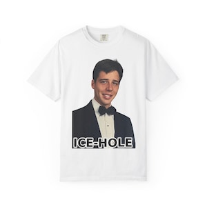 Peut inclure: T-shirt blanc avec une image imprimée d'un homme en smoking et nœud papillon. Le texte "ICE-HOLE" est imprimé en noir en dessous. Le t-shirt est de style décontracté, à manches courtes.