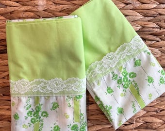 May include: Two folded pillowcases featuring a solid lime green top section and a white bottom section with a green floral pattern. A white lace trim with a rose motif separates the solid green fabric from the floral print fabric.